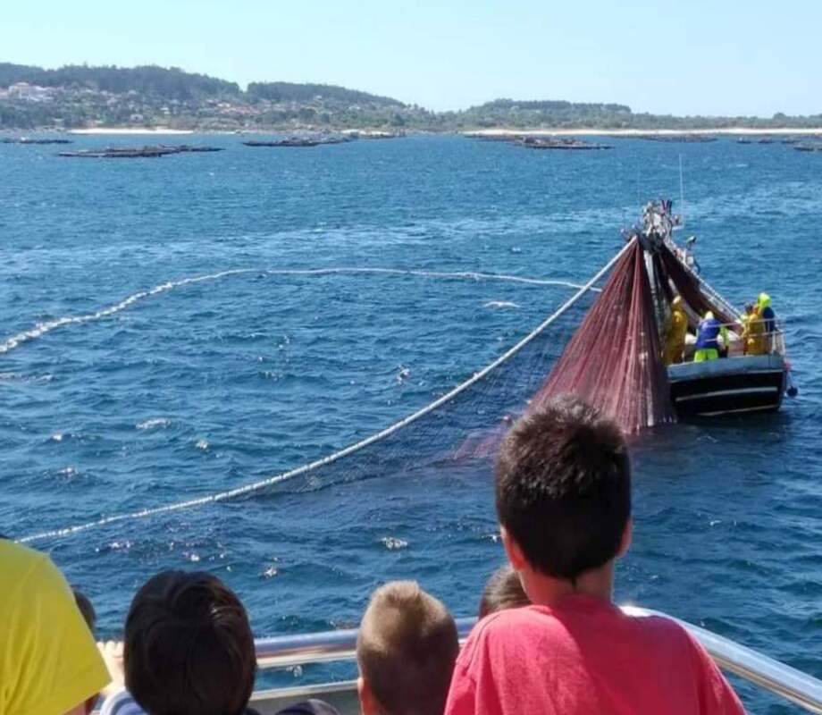 nin╠âos mirando barco faenando